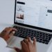 Hands typing on laptop searching Airbnb for accommodation options with map view