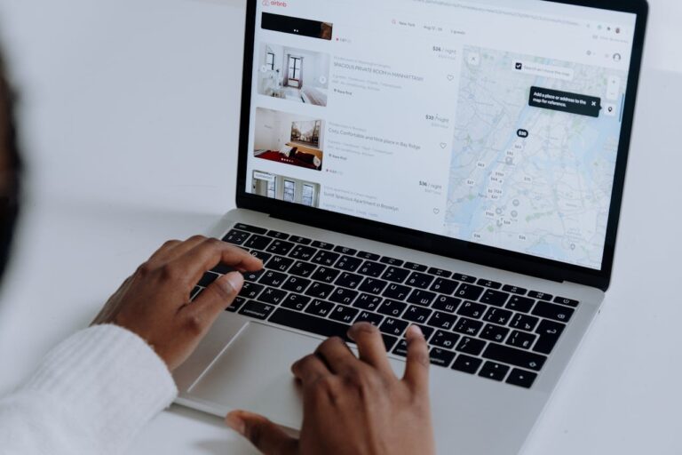 Hands typing on laptop searching Airbnb for accommodation options with map view