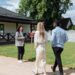A diverse group viewing a house for sale with a real estate agent outdoors.