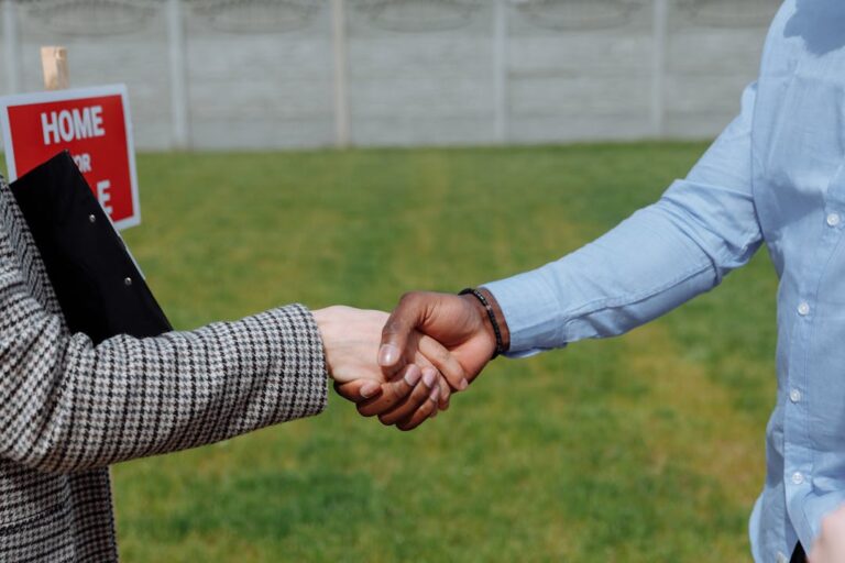Close-up of a handshake symbolizing a real estate agreement outdoors.